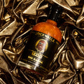 Spicewalla hot sauce bottle with black label and orange glass, close-up.