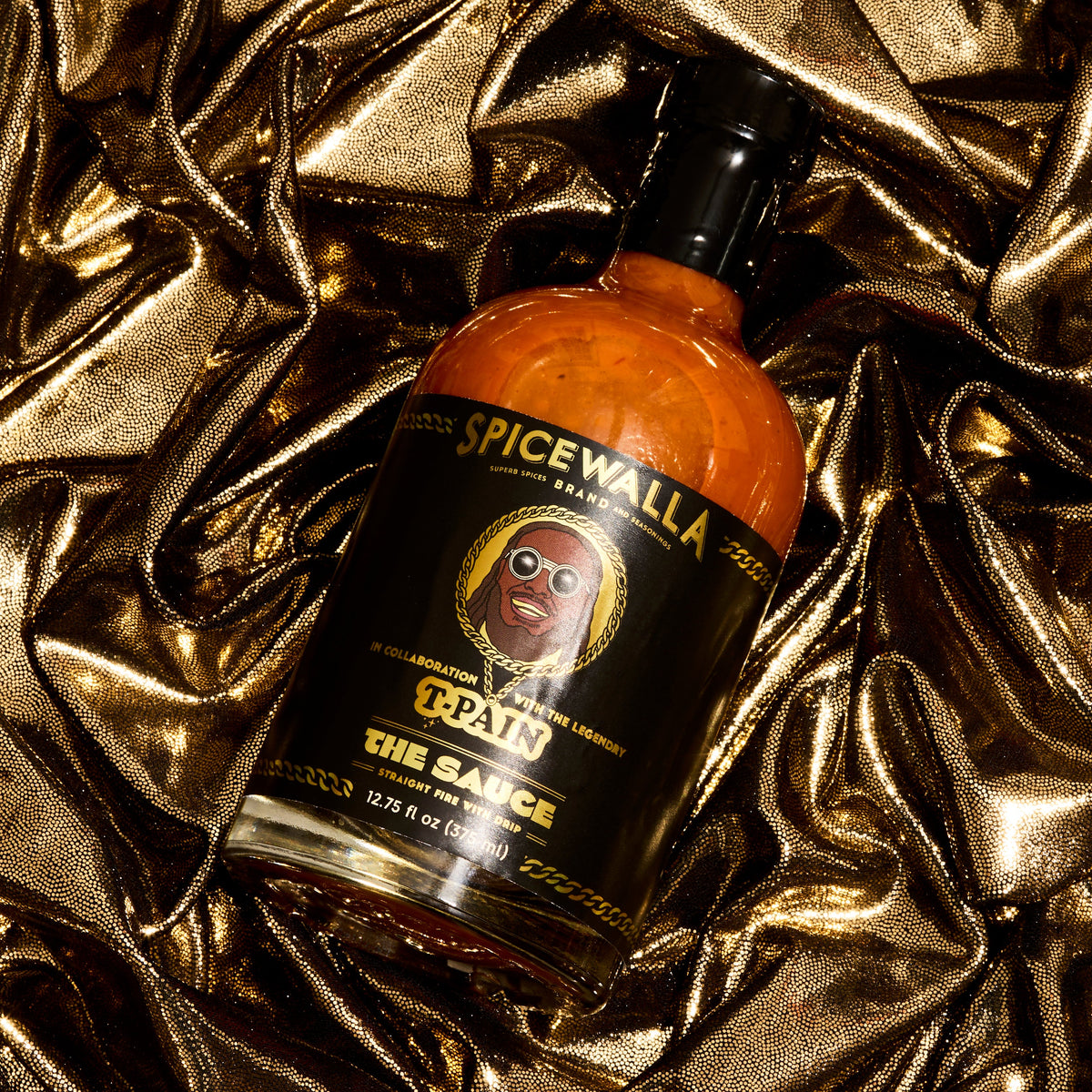 Spicewalla hot sauce bottle with black label and orange glass, close-up.