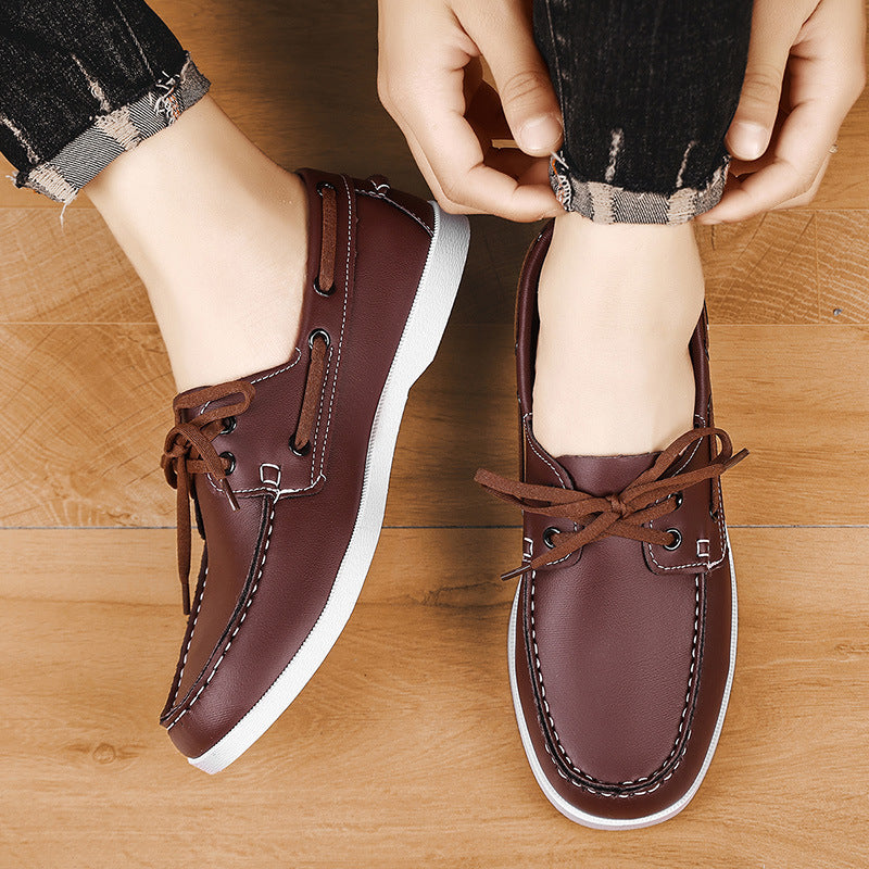 Men's brown lace-up loafers with white soles and visible stitching on wood floor