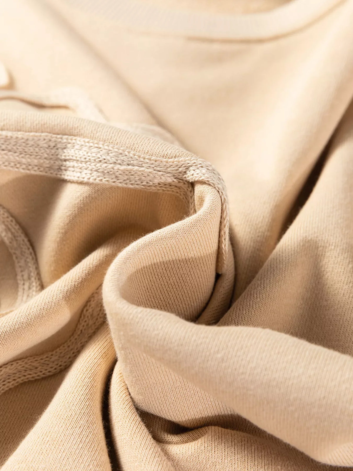 Beige sweatshirt fabric close-up with stitched seam and soft knit texture