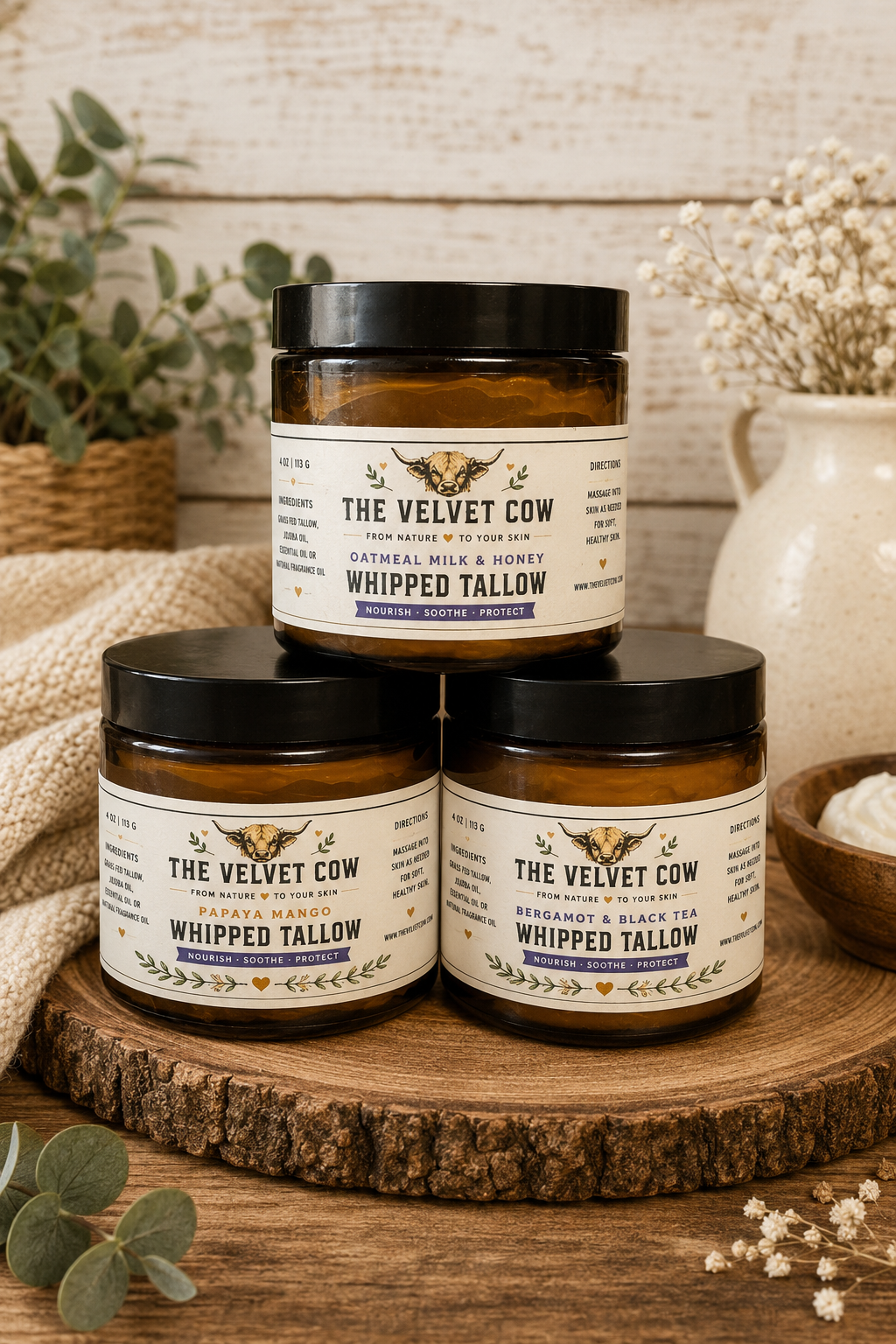 Three The Velvet Cow whipped tallow body butter jars stacked on wooden slab