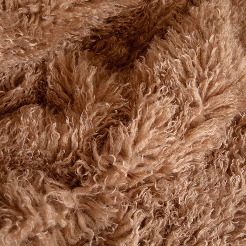 Close-up of tan curly plush faux fur dog bed fabric texture