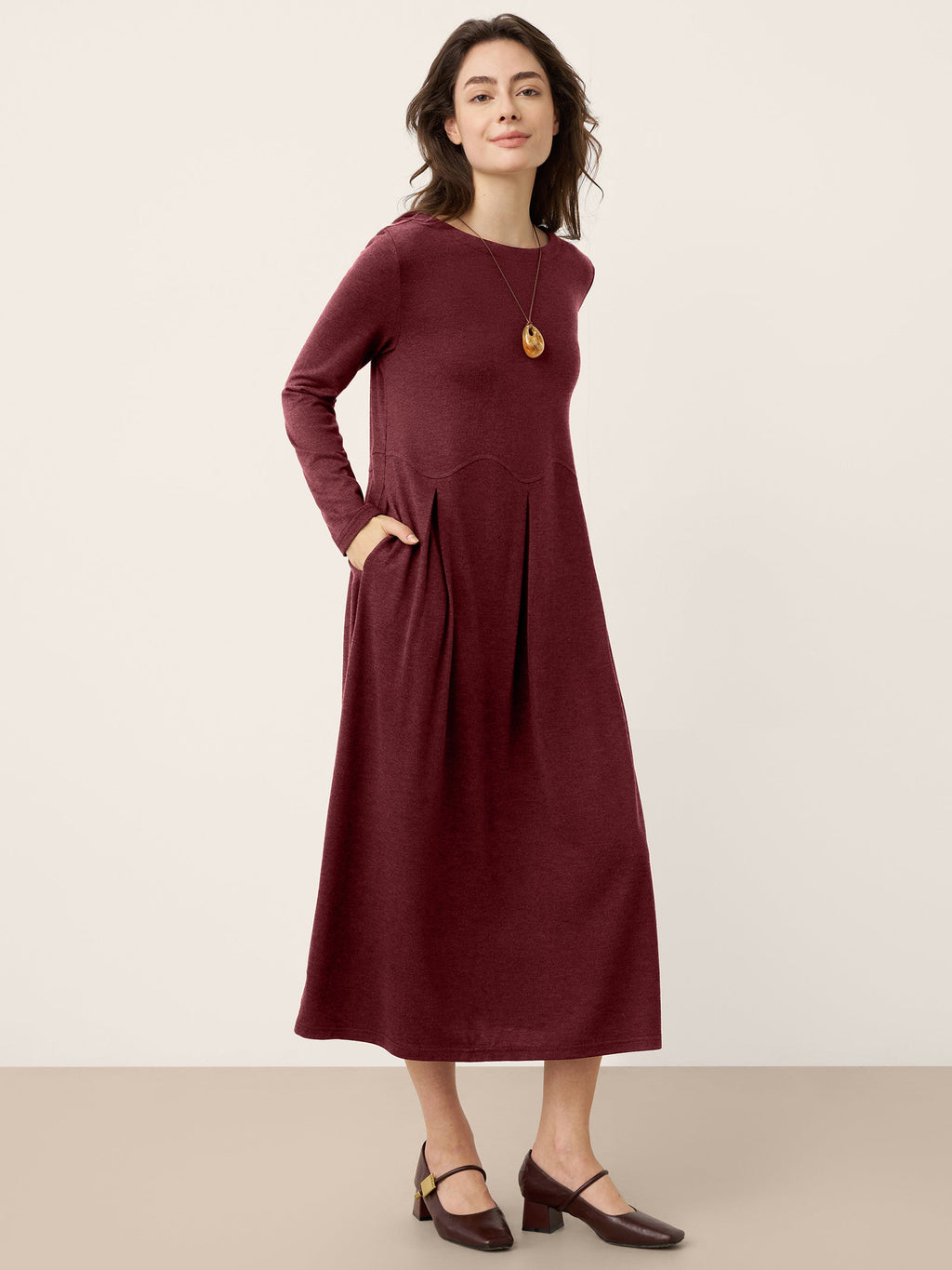 Raspberry red wool midi dress with long sleeves and pleated arc-panel skirt panels.