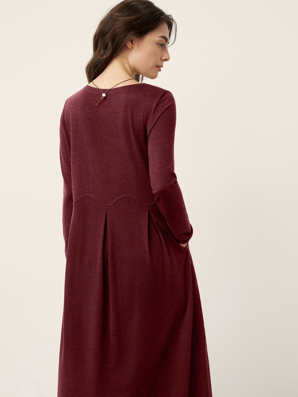 Raspberry red wool midi dress back view with pleated panels and buttoned slit detail.