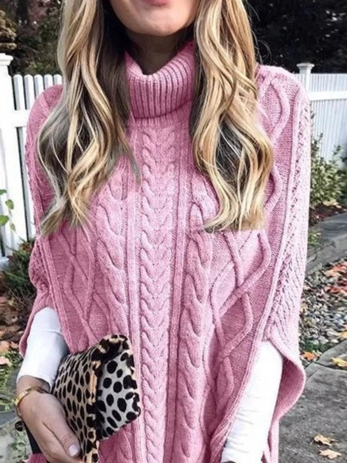 Pink chunky cable-knit turtleneck poncho with draped sides and cable pattern