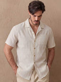 Men's beige striped short-sleeve button-up shirt on model with open collar