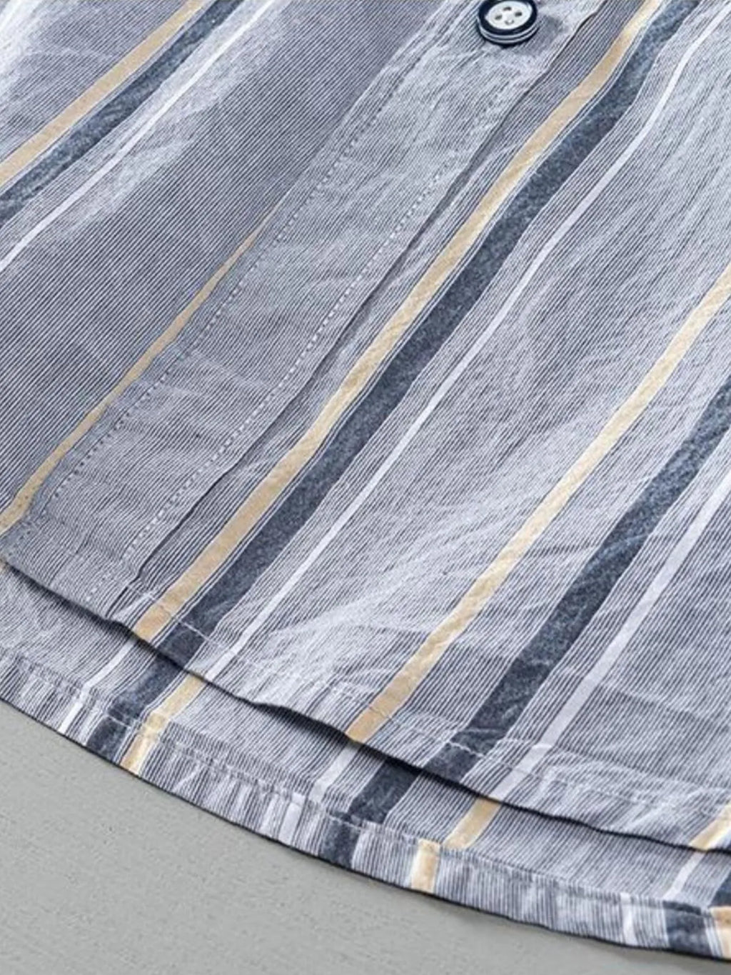 Light gray striped shirt hem with gathered stitching and subtle button details.