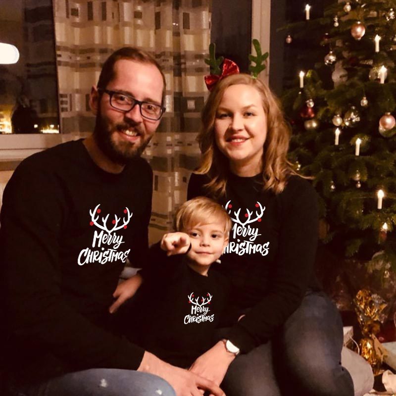 Black Christmas sweaters with reindeer 'Merry Christmas' print, family portrait of three.