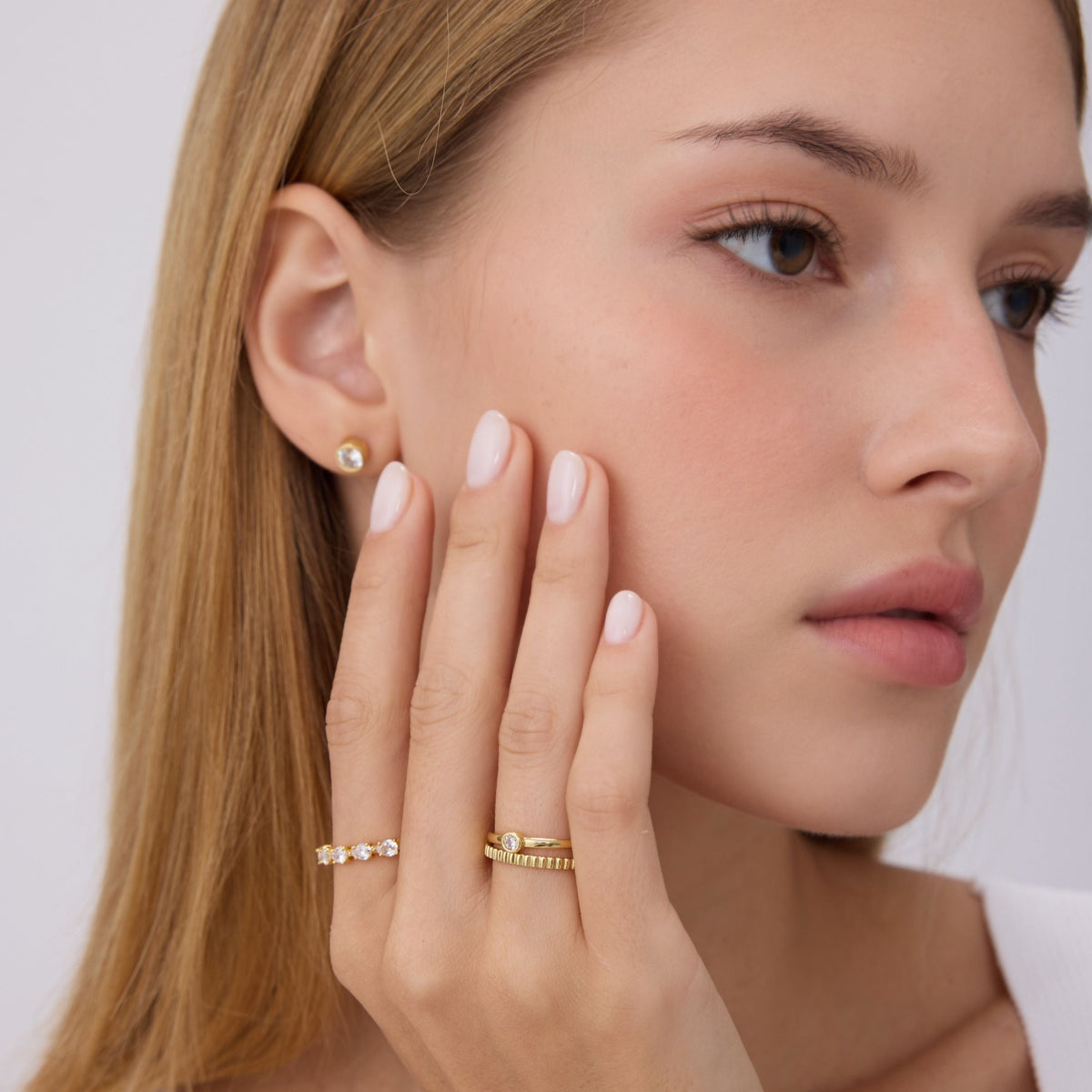 Gold bezel-set round stone ring on finger, slim band