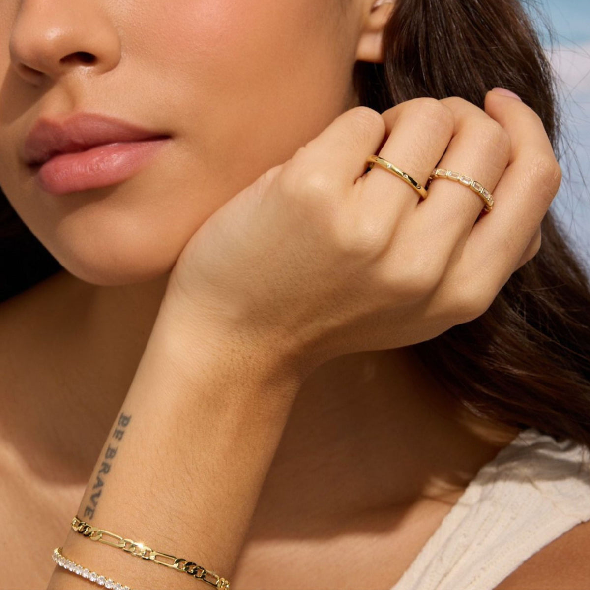 Gold-tone eternity band ring with rectangular clear stones, close-up on hand