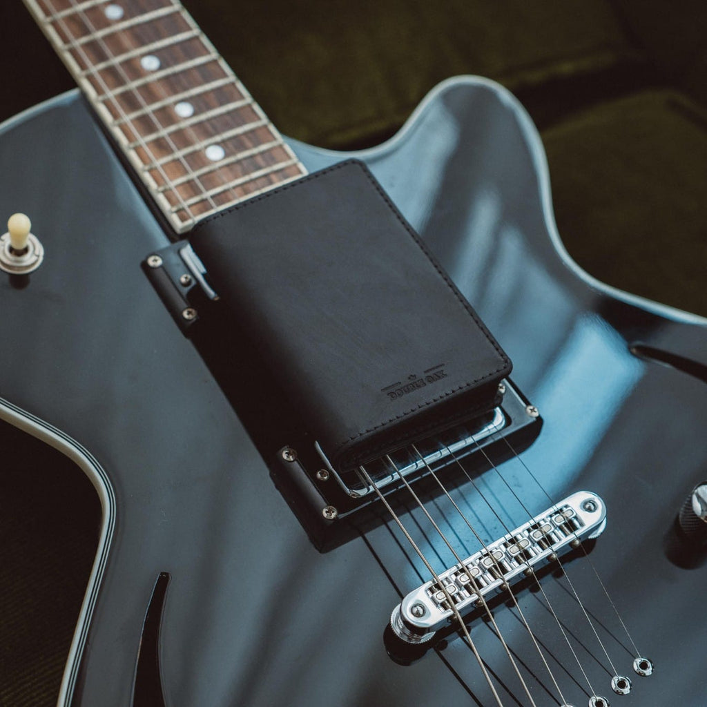 Bifold wallet, black leather, positioned on a blue electric guitar body.