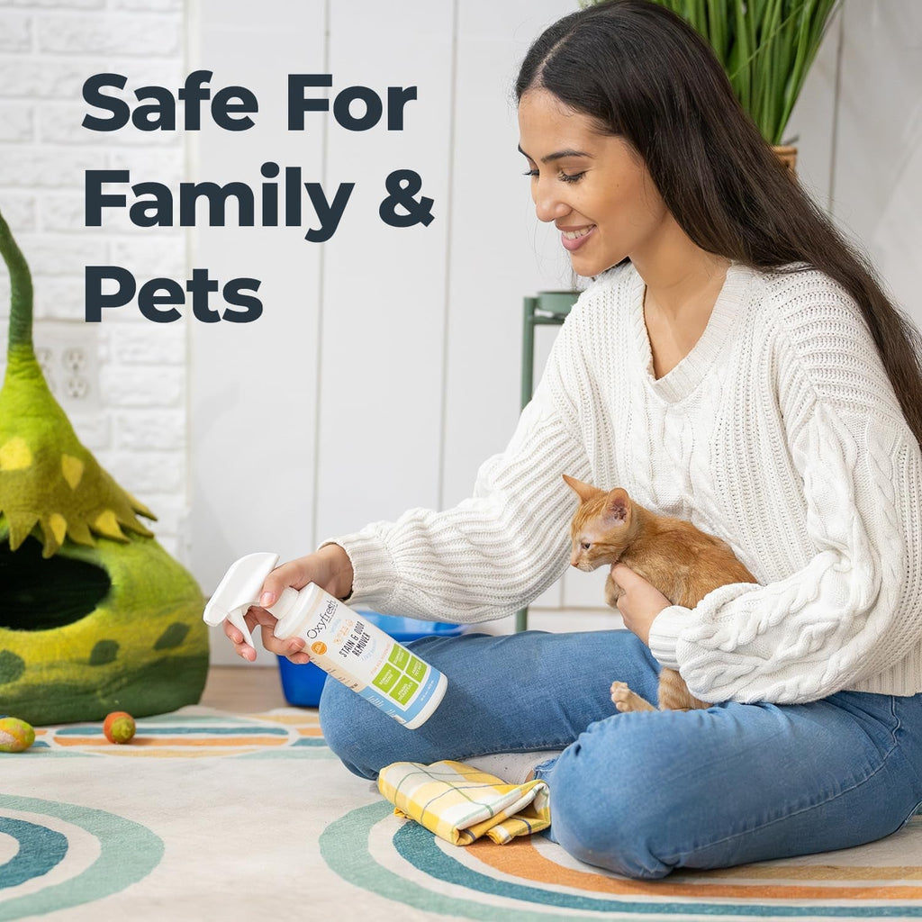 Oxyfresh stain and odor remover spray bottle held beside a cat