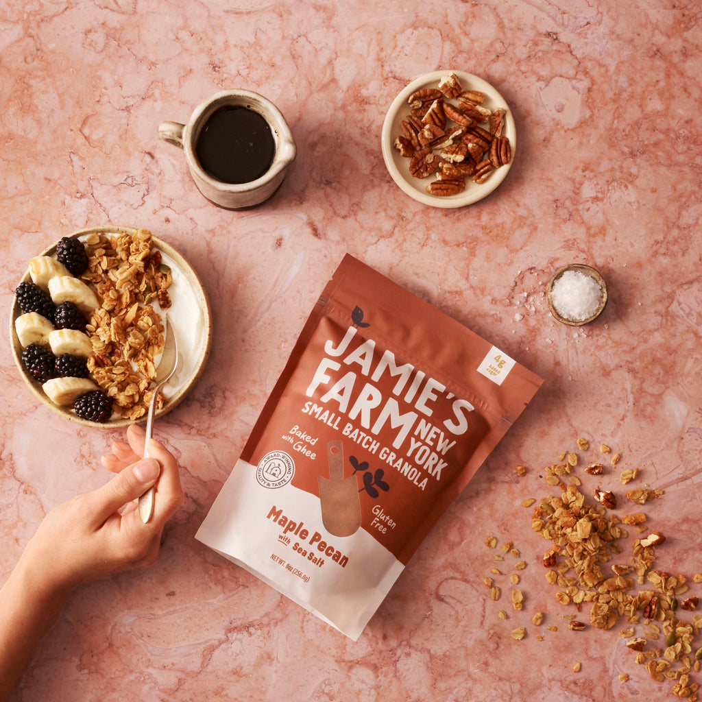 Maple pecan granola bag with sea salt with pecan pieces, cup of dark liquid, and spoon