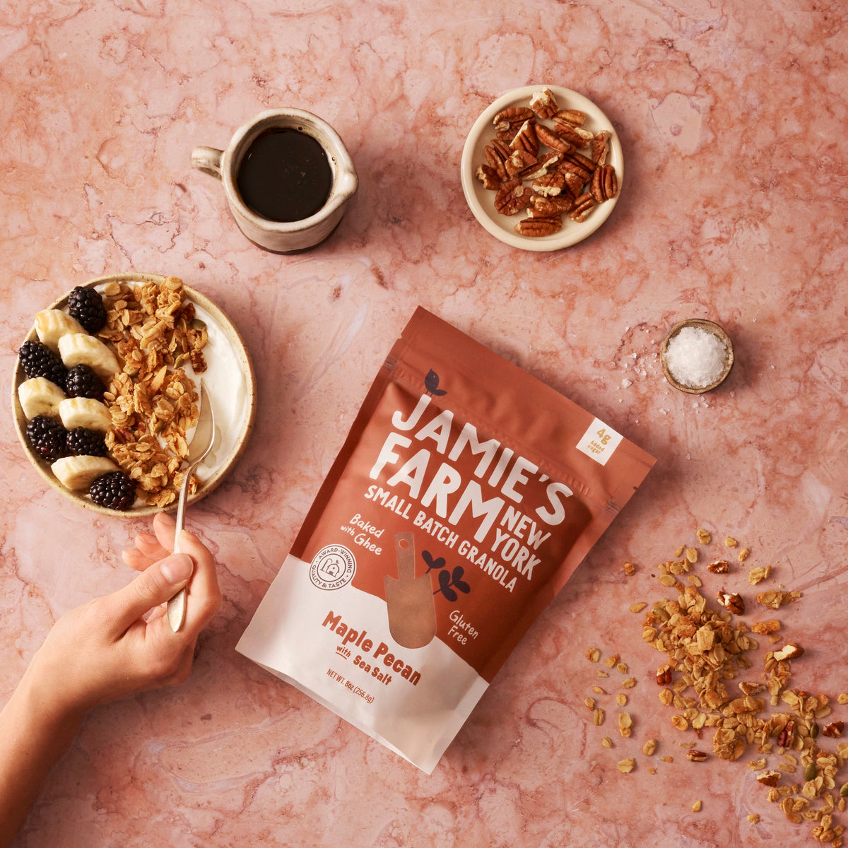 Maple pecan granola bag with sea salt with pecan pieces, cup of dark liquid, and spoon