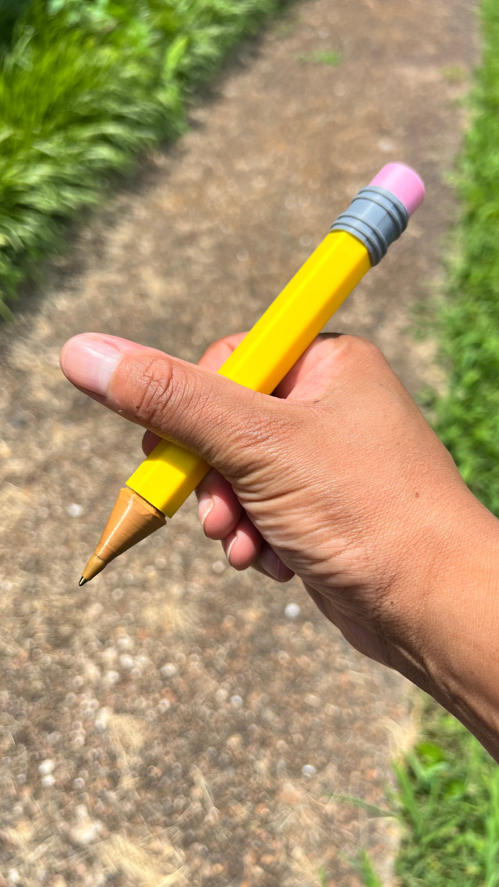 Jumbo yellow pencil in hand with pink eraser, gray striped band, wooden tip