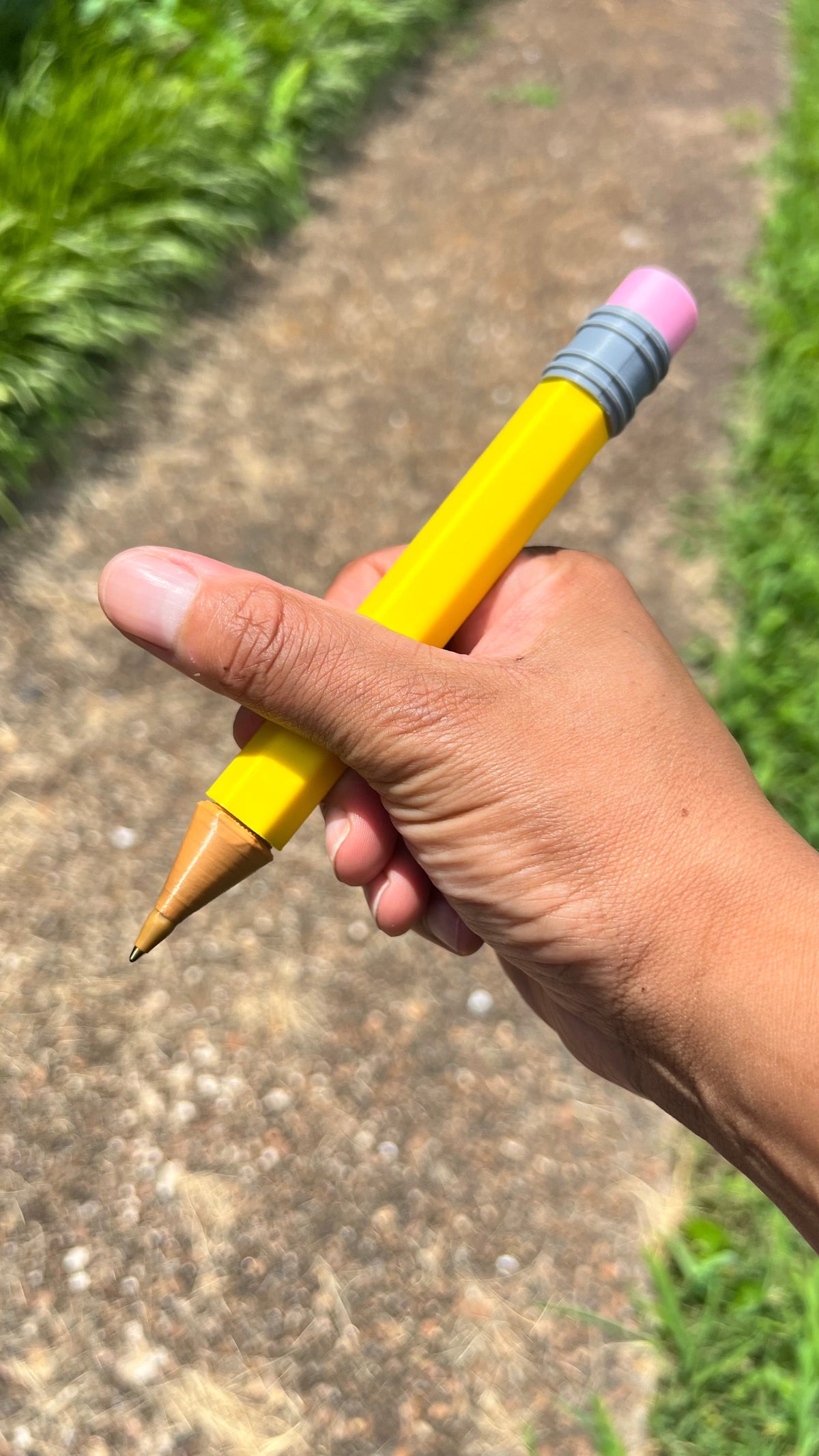 Jumbo yellow pencil in hand with pink eraser, gray striped band, wooden tip