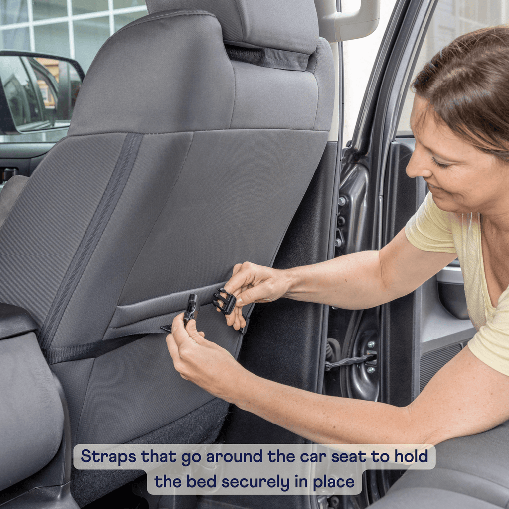 Gray tweed dog car bed with securing straps fastened around car seat