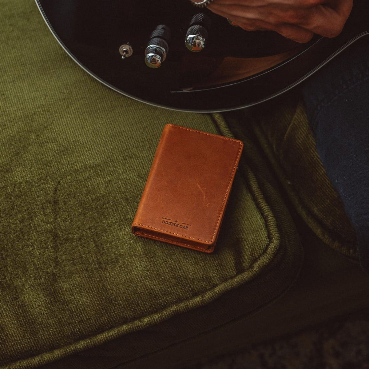 Bifold wallet, brown leather, front view resting on dark green fabric with stitched edge.