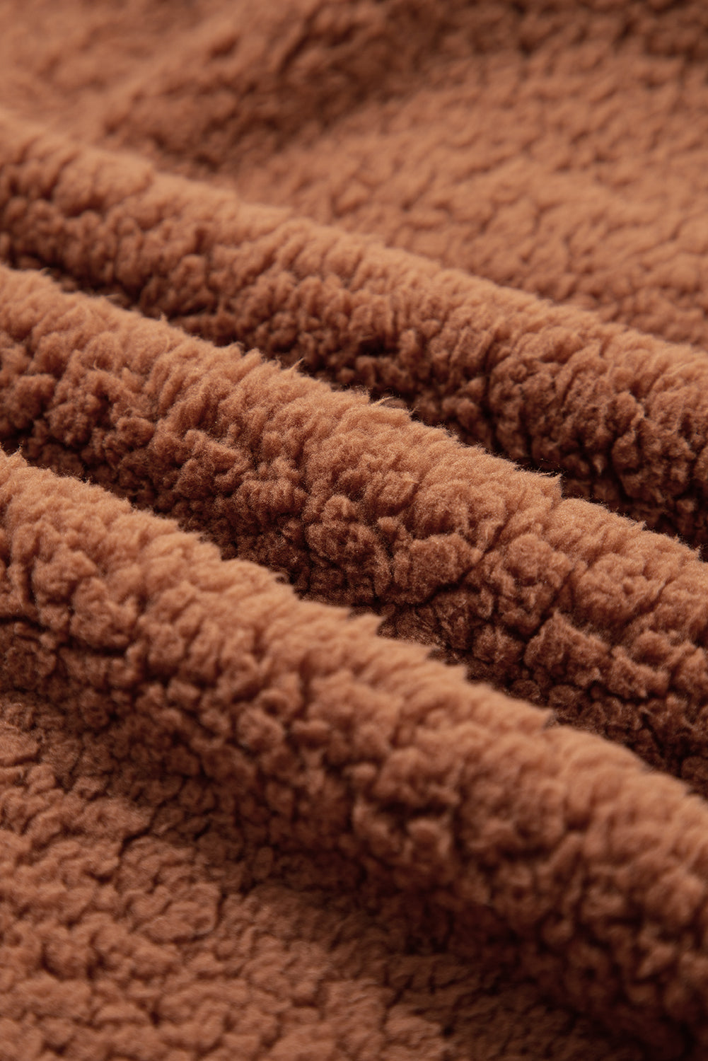Close-up of brown sherpa fleece texture on a zip-up hooded jacket