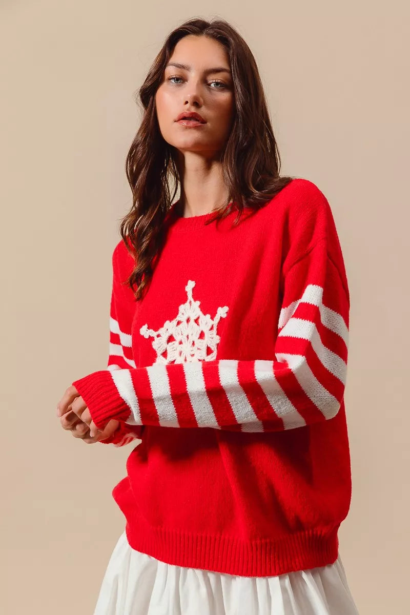 Red knit sweater featuring a white crochet snowflake on the chest and striped sleeves