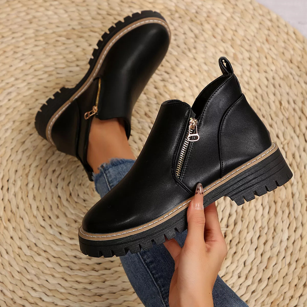 Black ankle boots with side zipper, tan stitching, and chunky lug sole