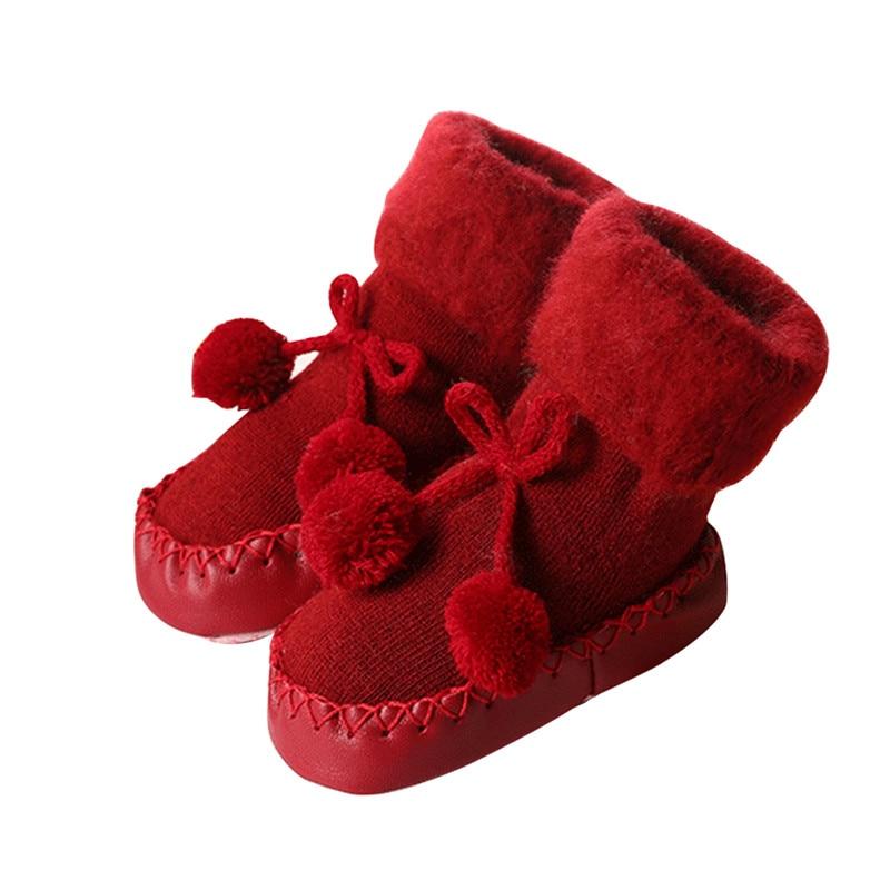 Pair of baby socks in red with pom-pom bows and stitched moccasin sole