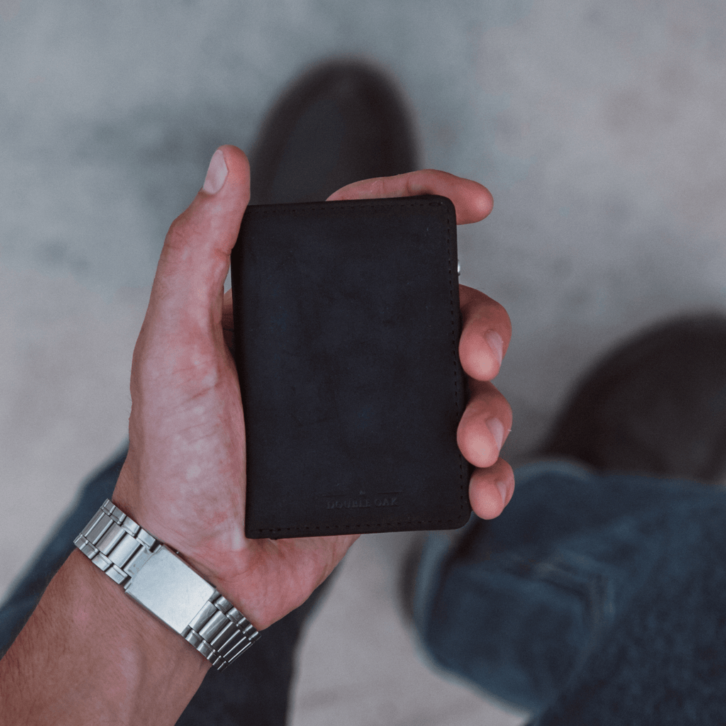 Black bifold wallet held in hand, smooth leather exterior.