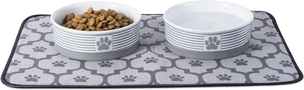 Two striped ceramic pet bowls on a paw-print feeding mat, one filled with kibble