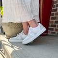 Women’s ivory sneakers with gray overlays, worn with white socks and blue jeans
