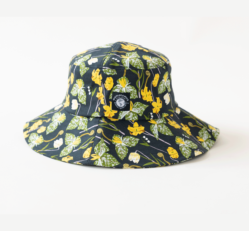 Floral cotton bucket sun hat, wide brim and round logo patch, dark background.