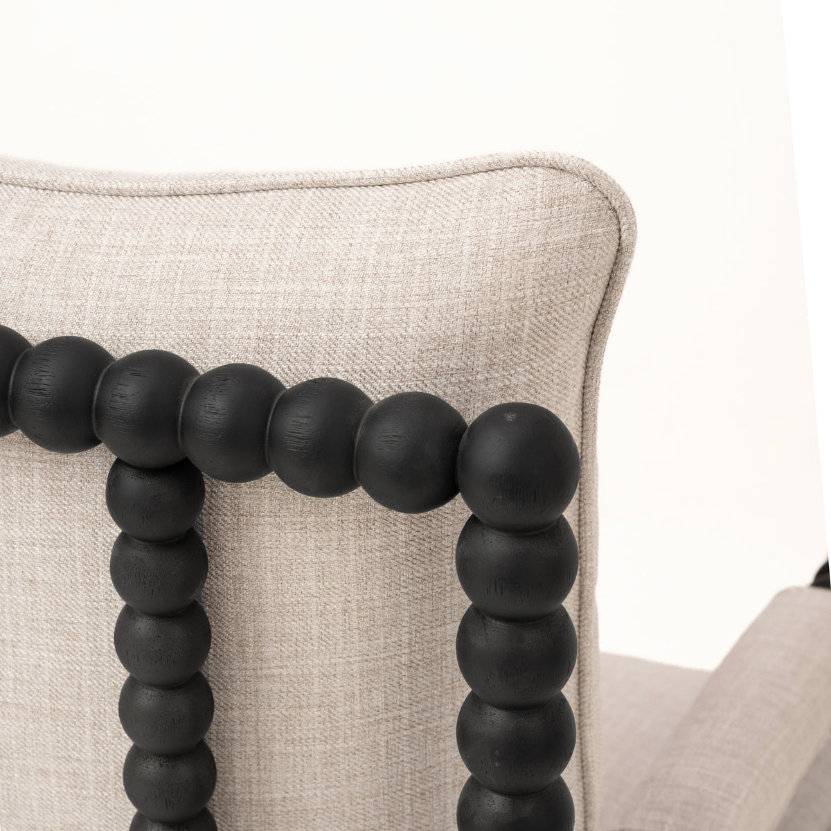 Accent chair detail showing textured cream fabric and rounded black wood frame