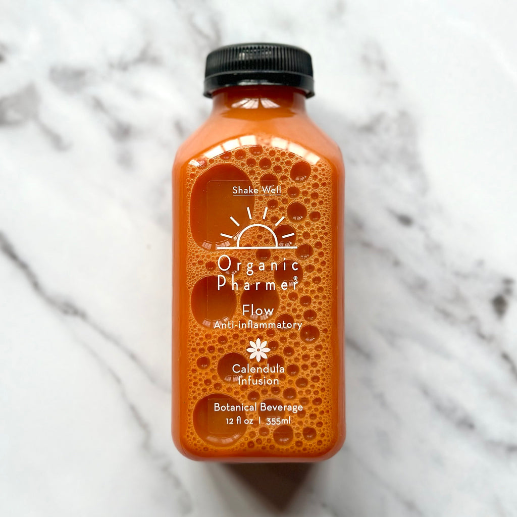 Organic Flow botanical beverage bottle, orange liquid, black cap, front label with icons.