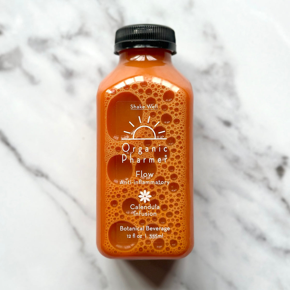 Organic Flow botanical beverage bottle, orange liquid, black cap, front label with icons.