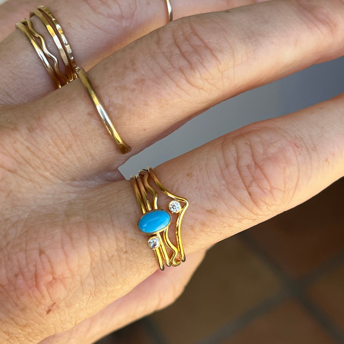 Gold-tone rings with oval turquoise cabochons and small clear stone accents