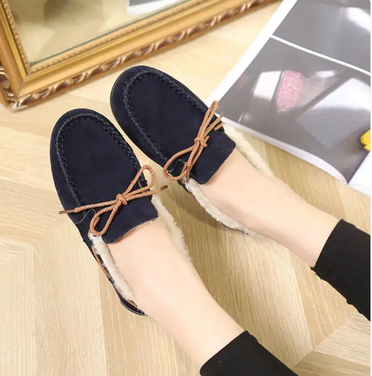 Navy plush slip-on moccasin flats with tan lace ties and white fuzzy lining