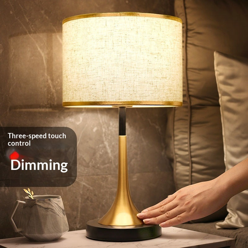 Gold table lamp with off-white fabric shade and dark round foot