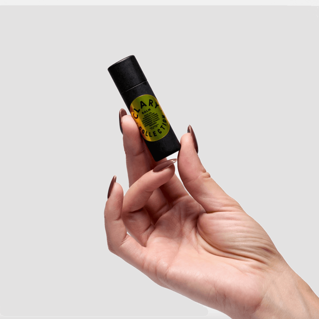 Olive balm stick held in hand, showing yellow center label