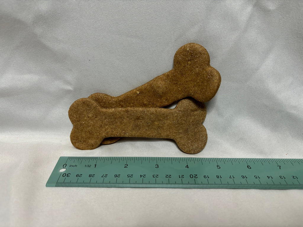 Two large bone-shaped dog biscuits shown beside a ruler for scale