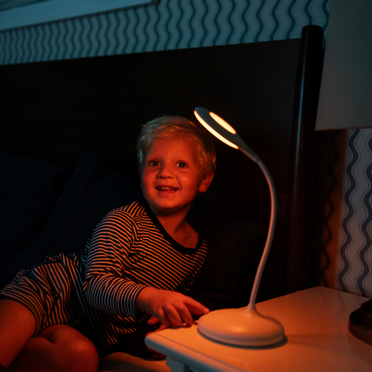 Small bedside table lamp with curved neck and glowing circular head