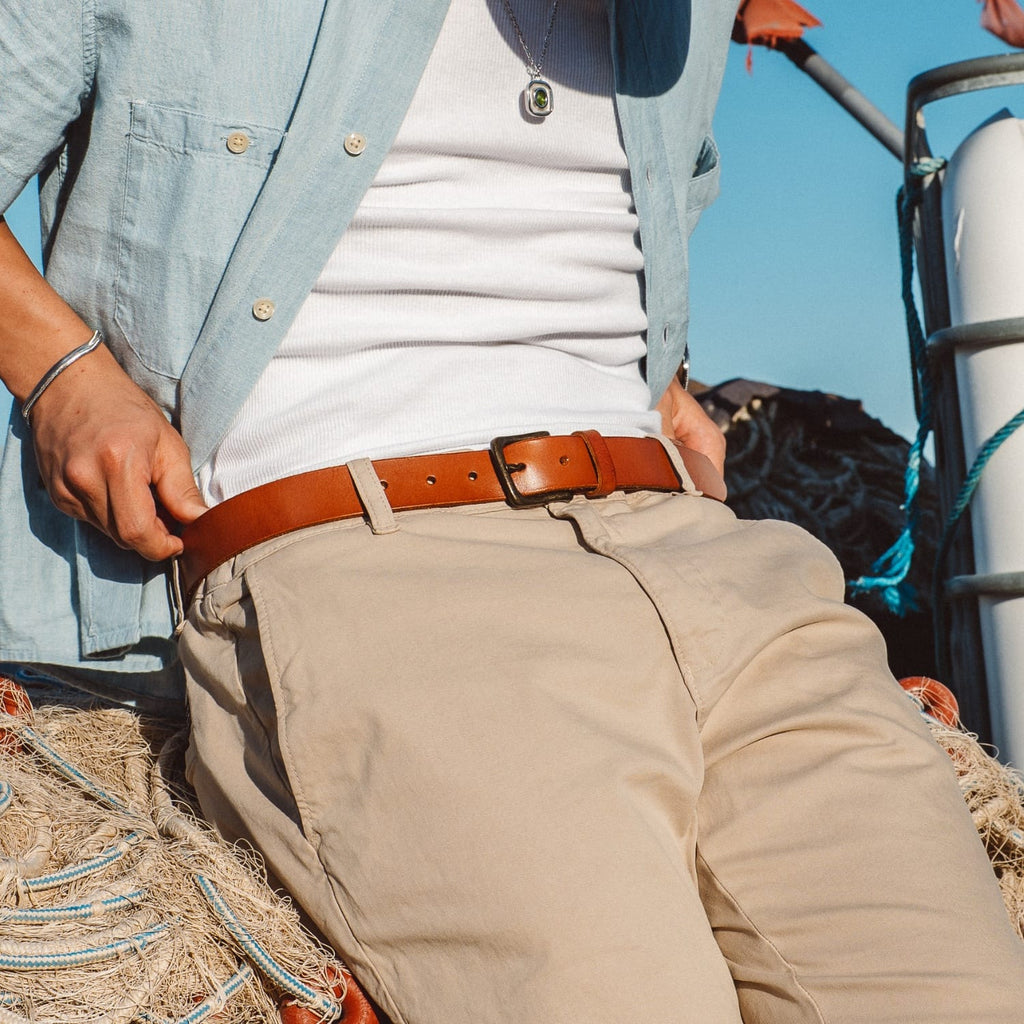 Brown leather belt with silver buckle on beige pants