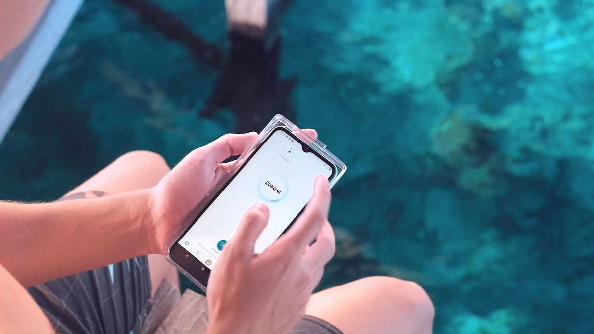 Hands holding a clear waterproof phone case with phone screen visible through window.