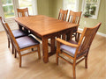 Rectangular wooden dining table with multiple chairs, dark brown upholstered seat pads.