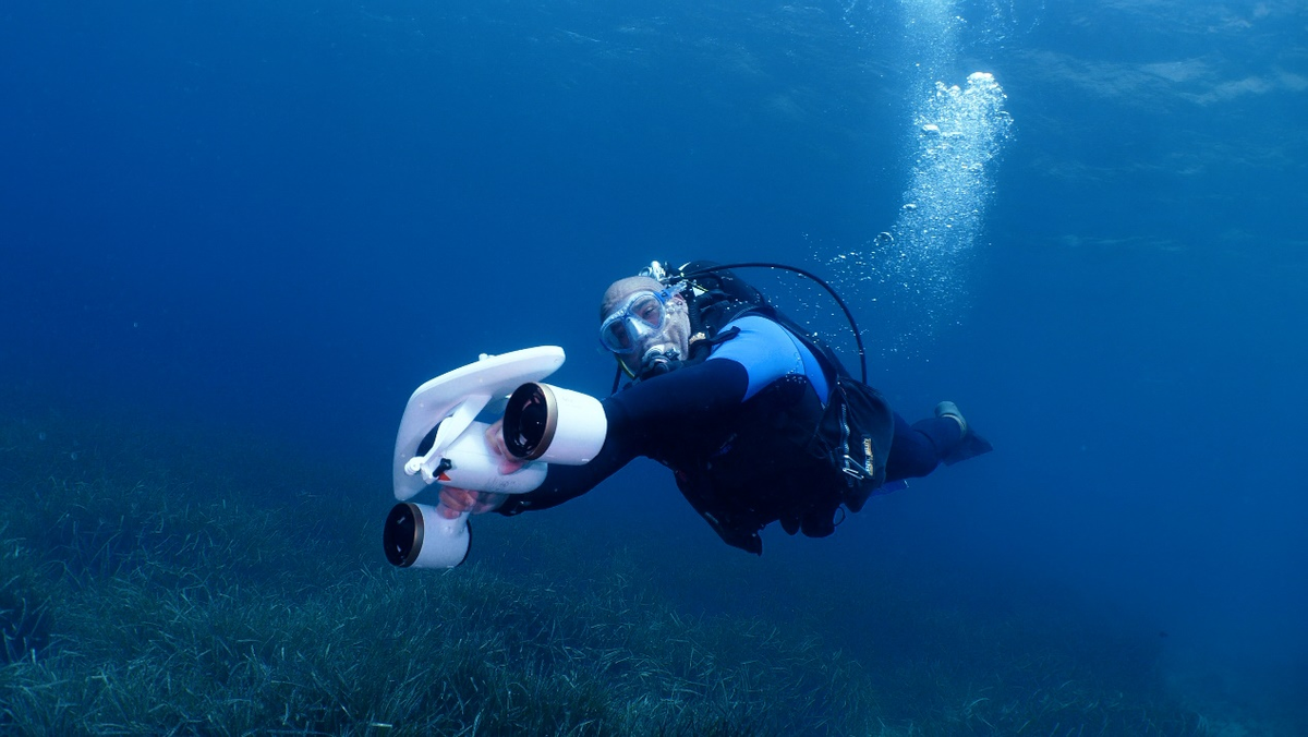 Underwater diver using a white camera housing and blue lighted gear