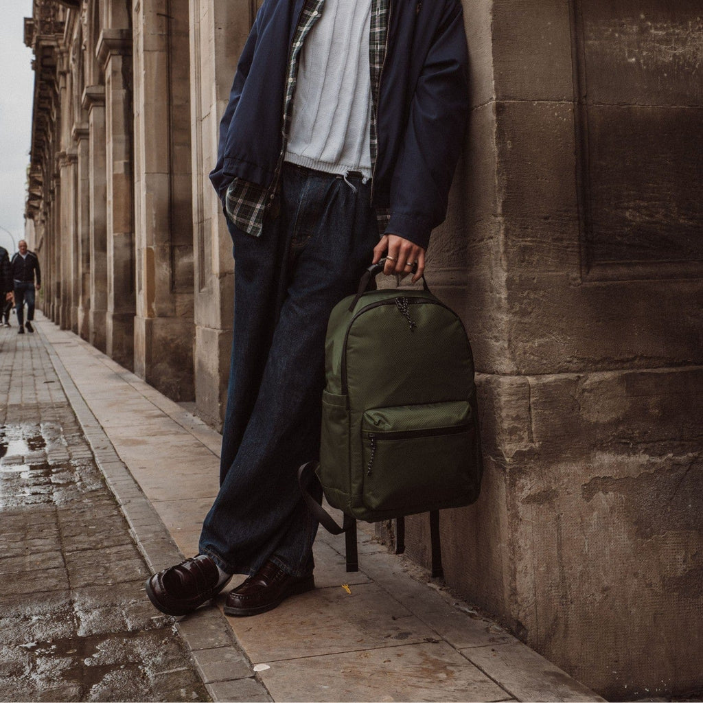 Olive-green backpack with front zipper pocket and adjustable shoulder straps.
