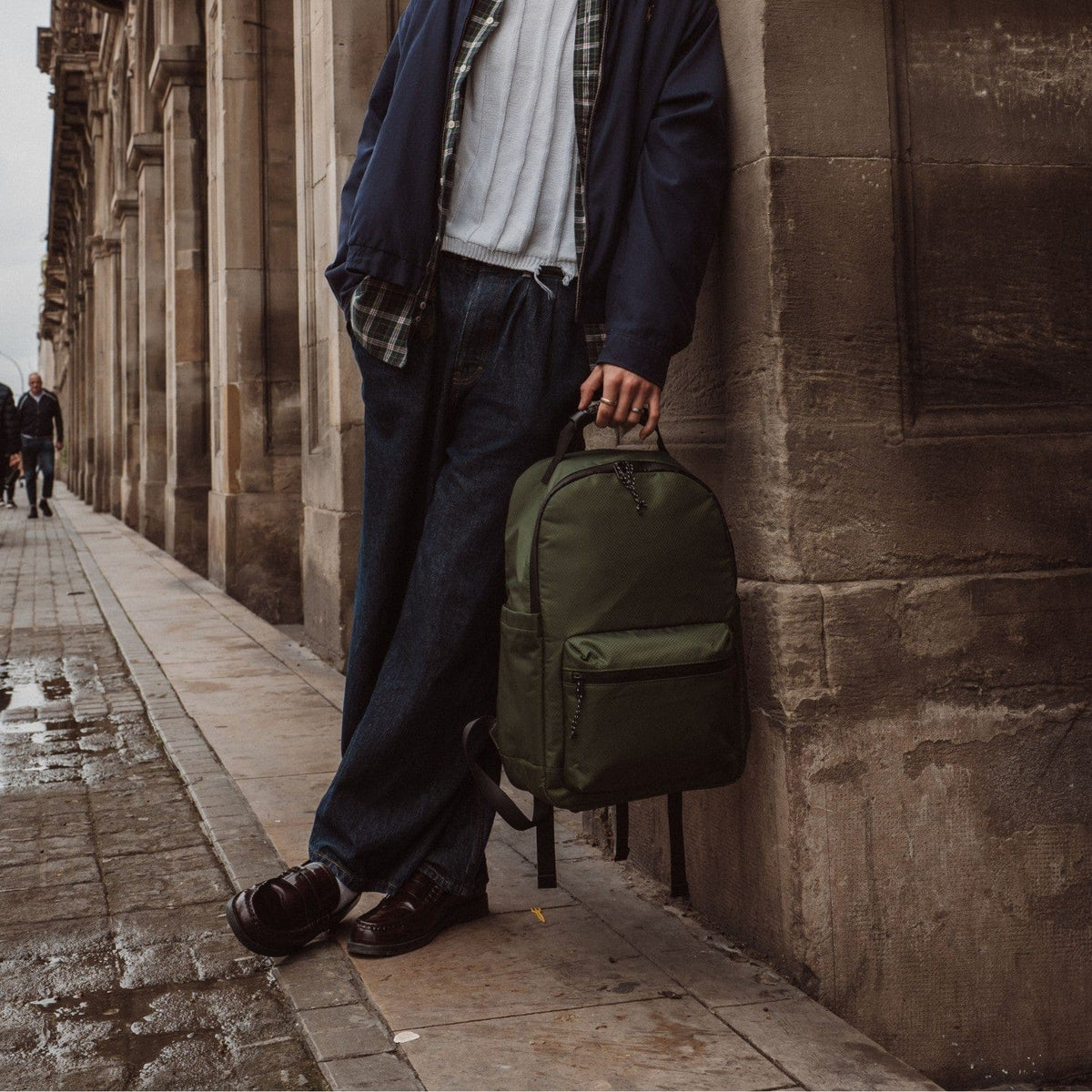 Olive-green backpack with front zipper pocket and adjustable shoulder straps.