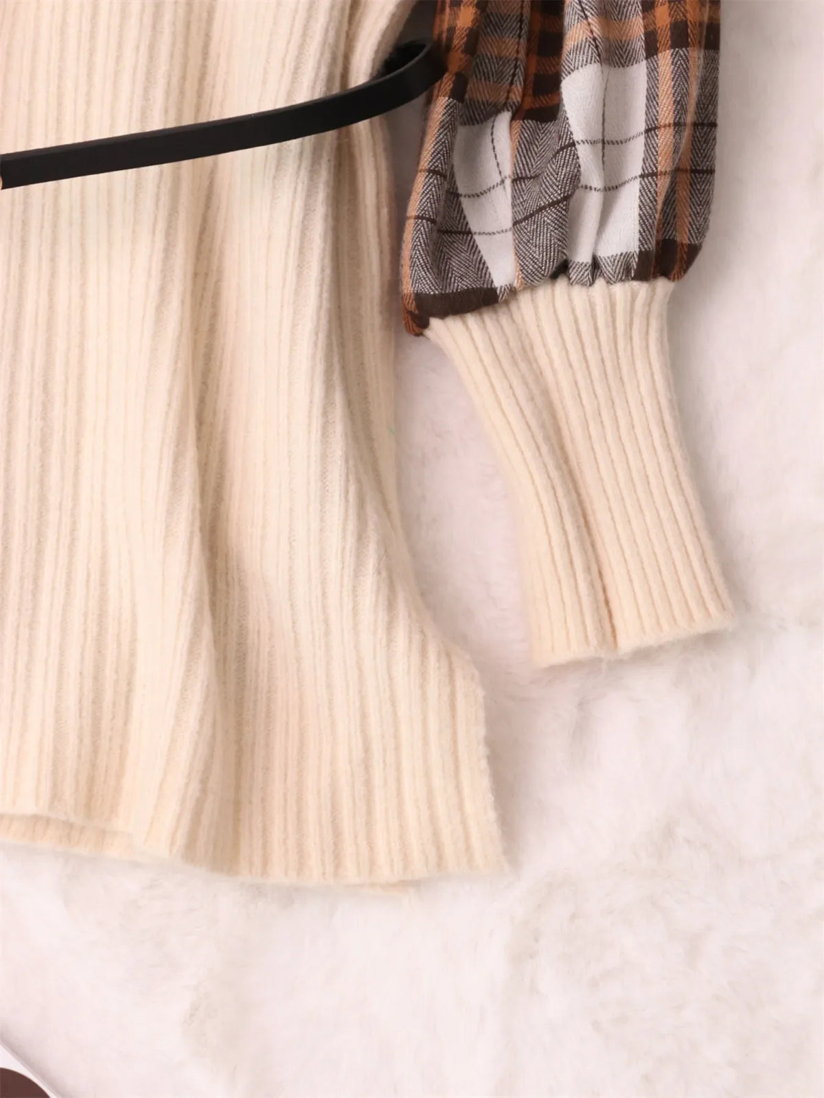 Cream sweater dress side view showing black belt and plaid sleeve cuff