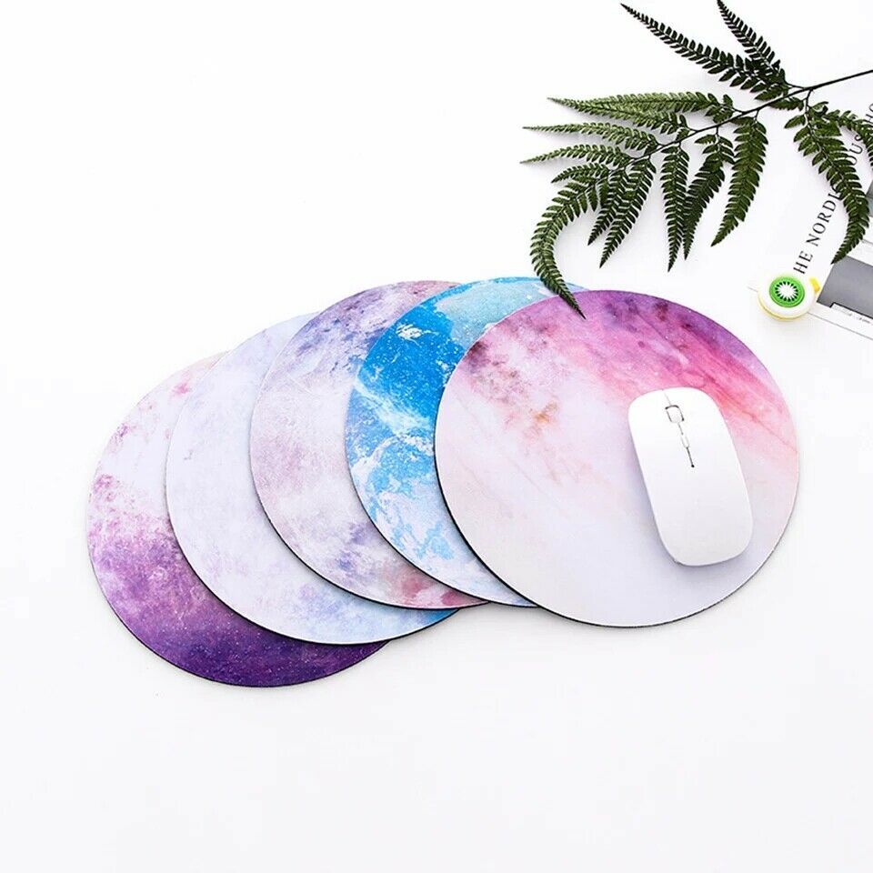 Set of round galaxy mouse pads stacked under a white mouse and keyboard setup