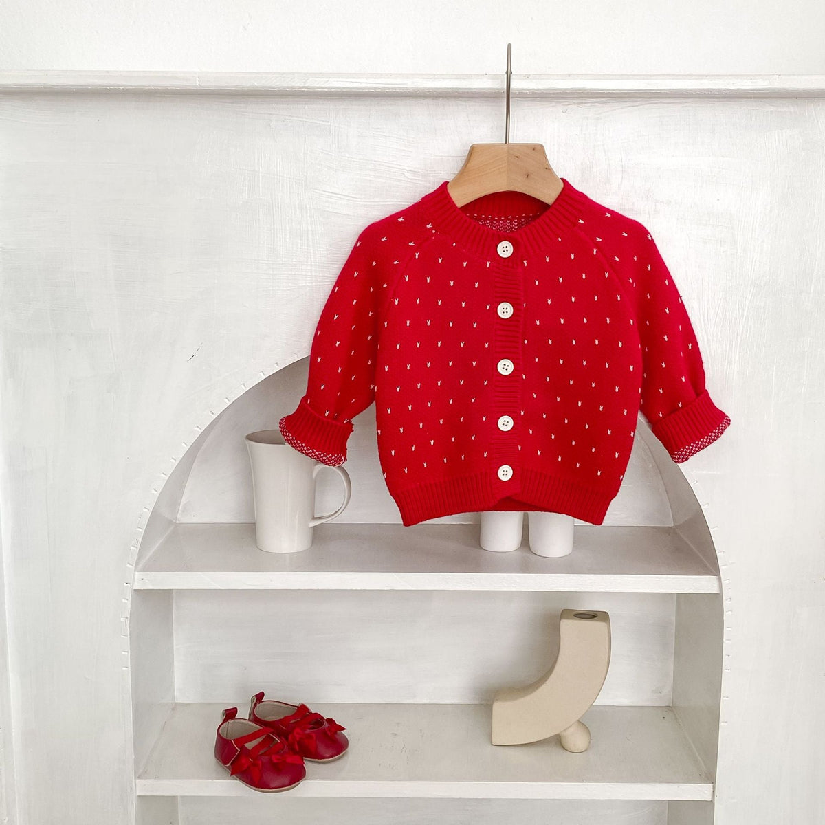 Red dot-pattern knit cardigan with round neckline and front button closures on hanger