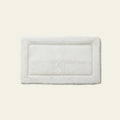 White rectangular bath mat with textured plush surface