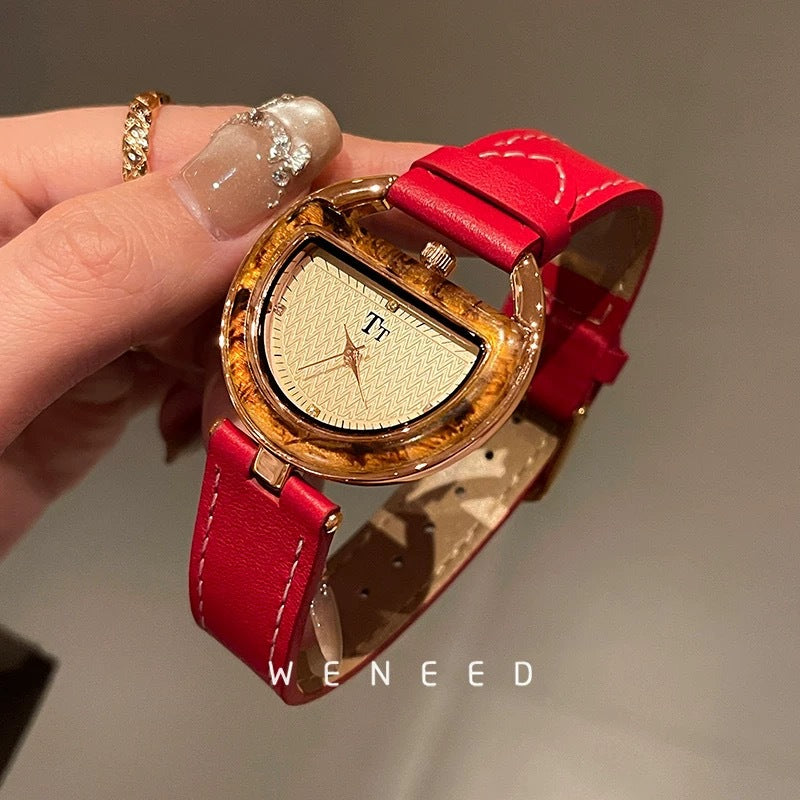 Women’s leather-strap watch with red band and gold-toned oval case, light dial.
